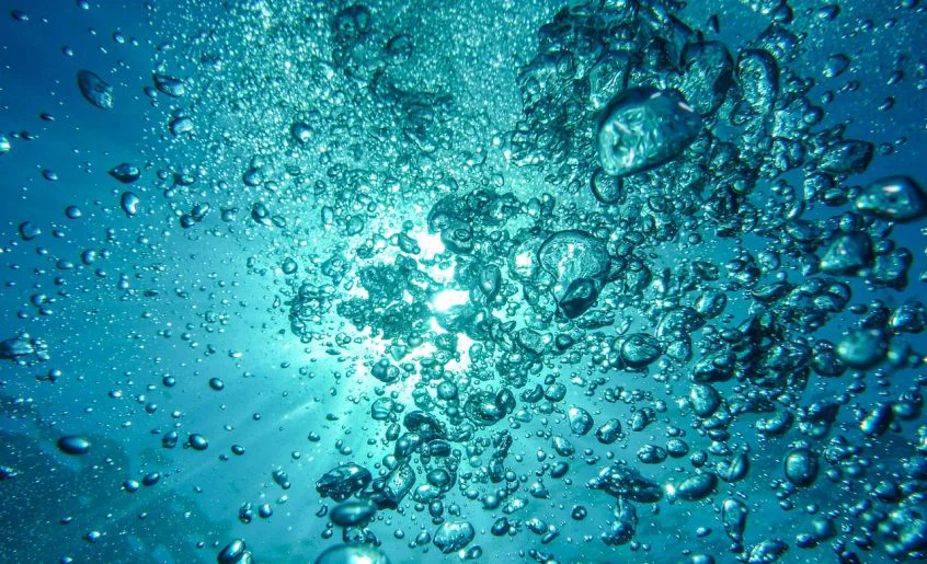 Burbujas emergiendo en agua clara como símbolo de creencias subconscientes que salen a la superficie.