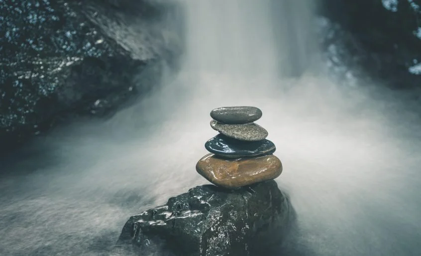 Cuatro piedras zen en cascada simbolizando las capas del trabajo con EFT Tapping.
